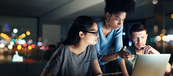 Team concentrating around a computer to drive successful business outcomes